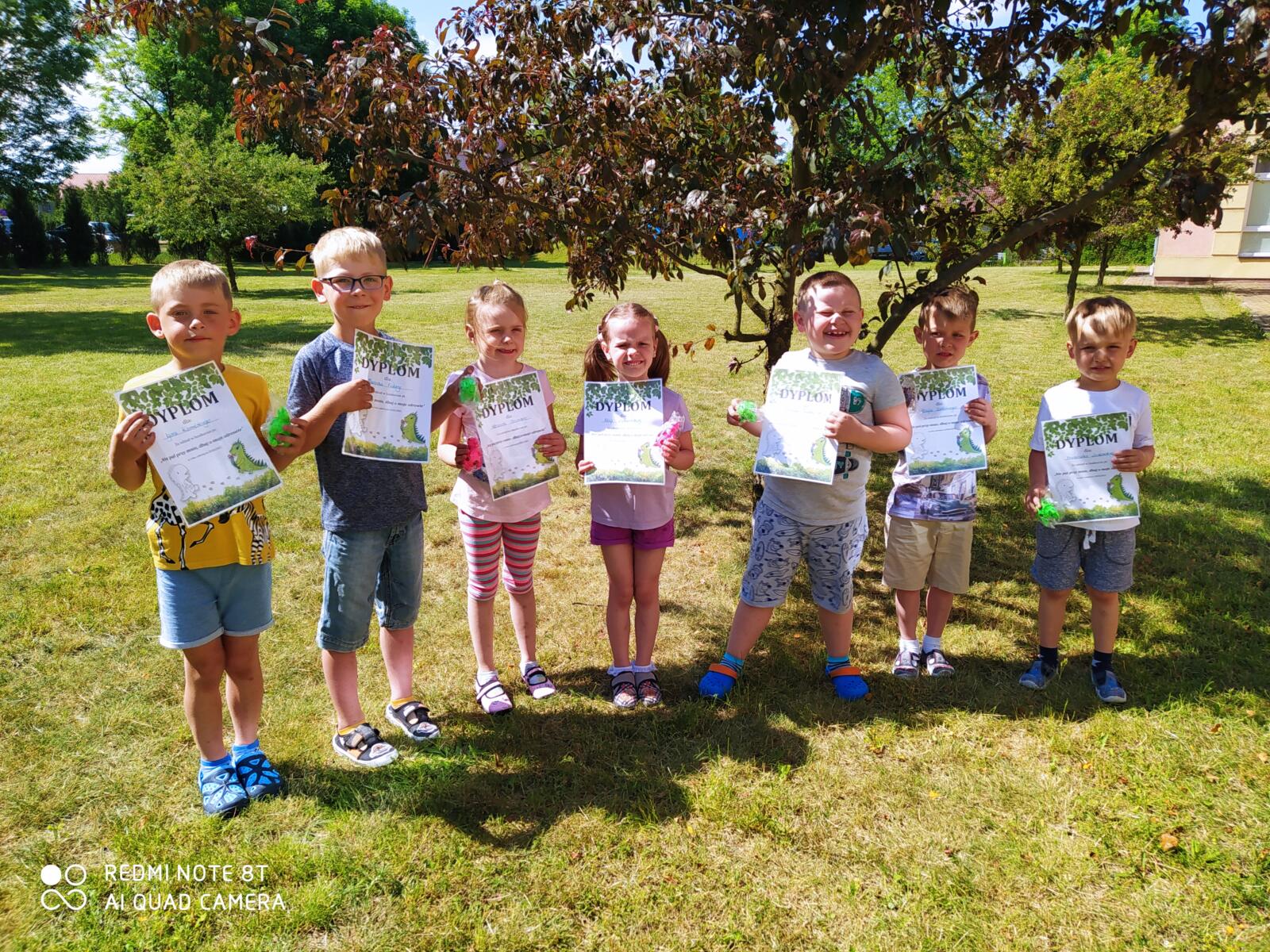 Zdjęcie przedstawia grupę dzieci nagrodzonych dyplomem i dinozaurem - gniotkiem za udział w konkursie "Nie pal przy mnie, dbaj o moje zdrowie"