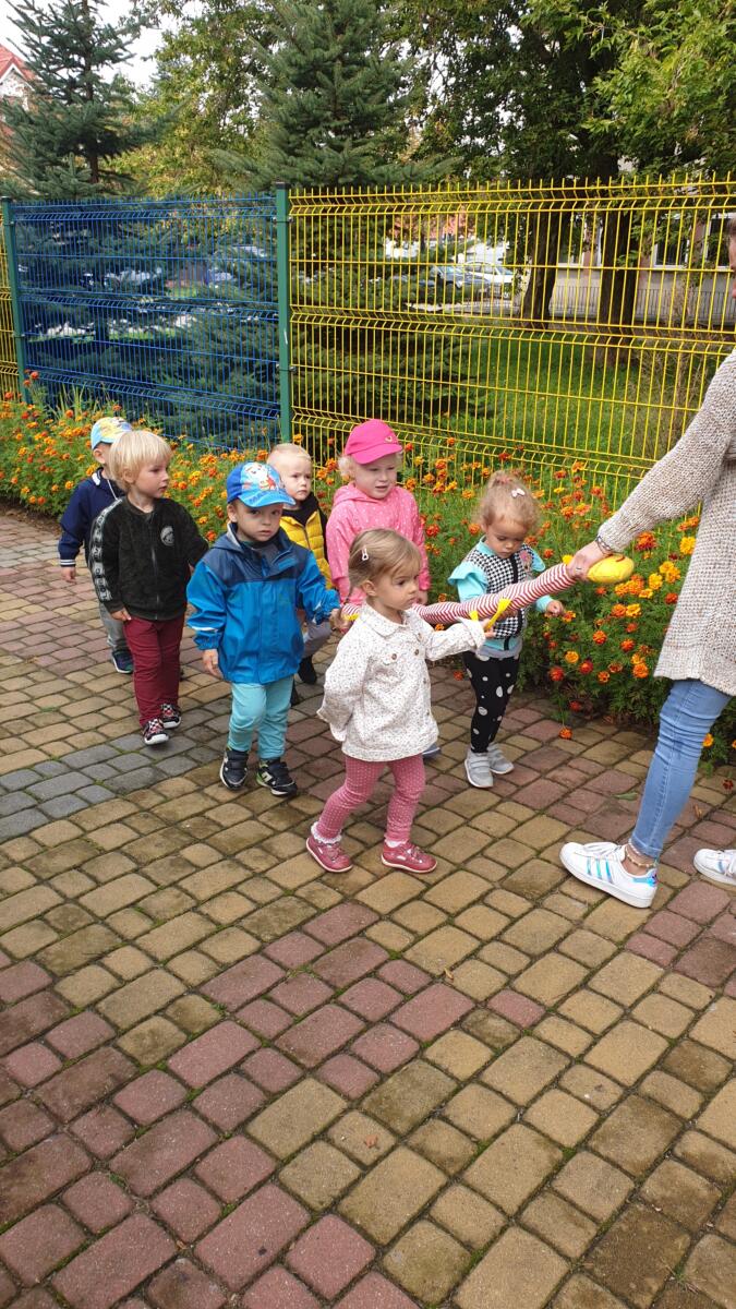 Przedszkolaki dzielnie maszerują z wężem na terenie przedszkola. Mimo pochmurnej pogody dzieci chętnie wyszły na świeże powietrze.