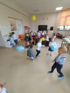 Zdjęcie przedstawia dzieci bawiące się przy muzyce z balonami.
