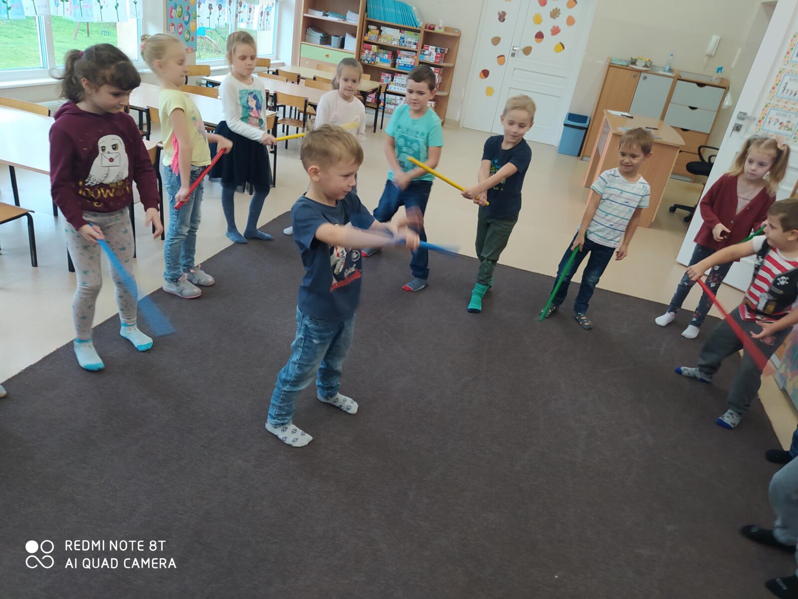 Zabawa przy muzyce z laseczkami - naśladowanie. W środku koła dziecko pokazuje rytmiczne ruchy laseczką według własnego pomysłu, reszta grupy naśladuje.