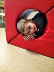 Na zdjęciu chłopiec przechodzący przez tunel stworzony z piankowych klocków.