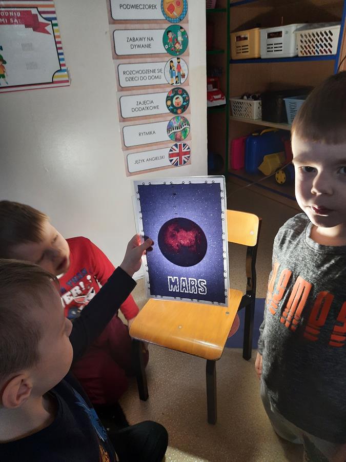 Chłopiec prezentuje "magiczny" obrazek - podświetlone lampą z tyłu widać na ilustracji planetę mars.