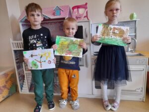 Na zdjęciu grupa dzieci, które prezentują wykonane przez siebie prace.