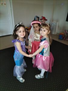 Zdjęcie przedstawia dziewczynki w strojach balowych tańczące w kółeczku.