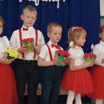 Dzieci wręczają upominki dla nauczycieli: bukiety kwiatów z papieru
