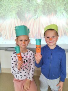Na zdjęciu dzieci w opaskach marchewek prezentują swoje "marchewki"wykonane z rolek po papierze toaletowym.