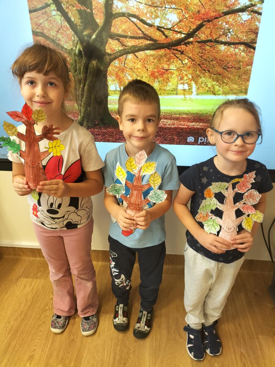 Zdjęcie przedstawia dzieci, które prezentują wykonane przez siebie "Jesienne drzewka".