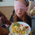 Dziewczynka z zakrytymi oczami smakuje owoce