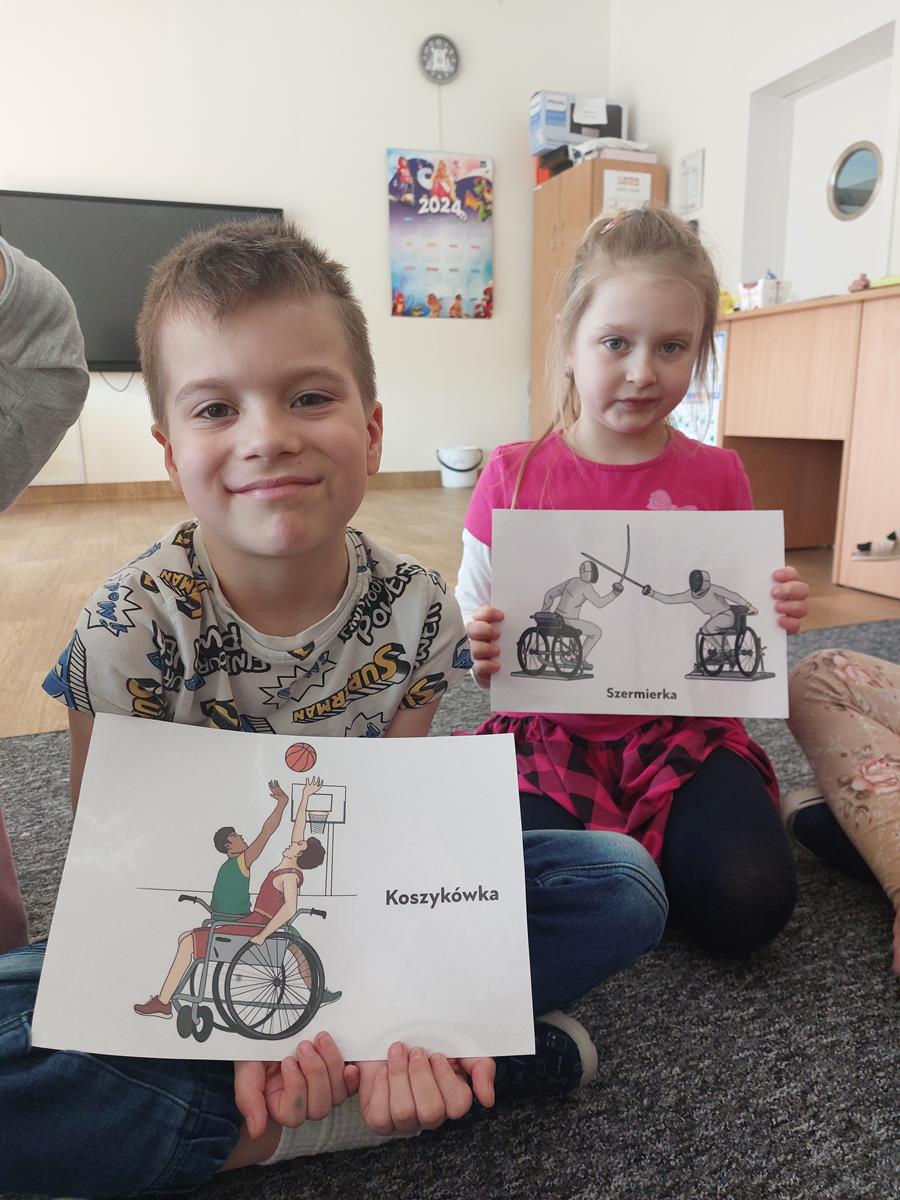 Dzieci pokazują ilustracje o osobach niepełnosprawnych.