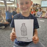Chłopiec trzyma kartę obrazkową z woda gazowana ang. Sparkling water.