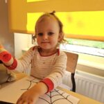 Dziewczynka w trakcie wykonywania pracy plastycznej -pająki.