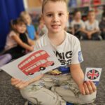 Chłopiec ukazuje karte obrazkową 'double-decker bus'.