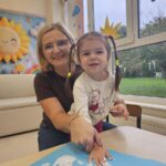 Dziewczynka akceptuje zasady poprzez odciśnięcie swojej rączki pomalowanej białą farbą na brystolu z zasadami.