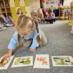 Dziewczynka rozkłada karty obrazkowe do piosenki.