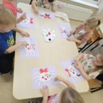 Dzieci przy stoliczku wykonujące prace plastyczna - pajączka