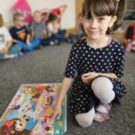 Dziewczynka wskazuje wybrane słówko przez nauczyciela na plakacie.