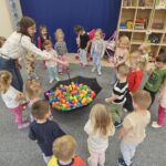 Dzieci podczas zabawy z parasolką i kulkami.