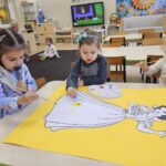 Trzy dziewczynki malują wspólnie farbami Królewnę Śnieżkę.