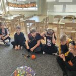 Dzieci słuchaja bacznie i powtarzają nowego słownictwa. Przyglądają sie obrazkom na plakacie.