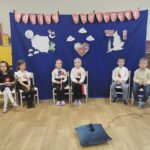 Zdjęcie ukazuje małych artystów, siedzących na scenie. Dzieci czekają aż zaprezetują puosenki i wierszyki na scenie przed publicznością.