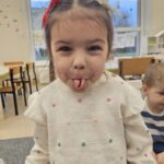 Dziewczynka robi z języka rulonik. Ćwiczy swój aparat artykulacyjny.