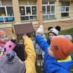 Dzieci dokarmiają ptaki - wkładają pokarm do karmnika.