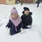 Dwójka dzieci w trakcie zabaw na śniegu.