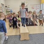 Chłopiec idzie po ławce , próbuje utrzymać równowagę.