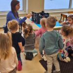 Nauczyciel ukazuje dzieciom legende o Smoku Wawelskim. Ba zdjeciu widać dzieci obserwujące nauczyciela.