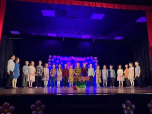 Zdjęcie przedstawia dzieci na scenie podczas recytacji wierszyków. 