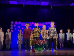 Zdjęcie przedstawia dzieci na scenie podczas recytacji wierszyków. 