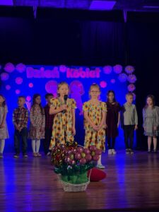 Zdjęcie przedstawia dzieci na scenie podczas recytacji wierszyków. 