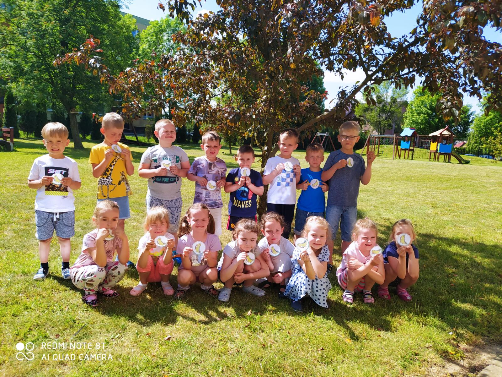 Zdjęcie przedstawia grupę Reniferki w ogrodzie przedszkolnym z medalami za udział w programie "Czyste powietrze wokół nas".