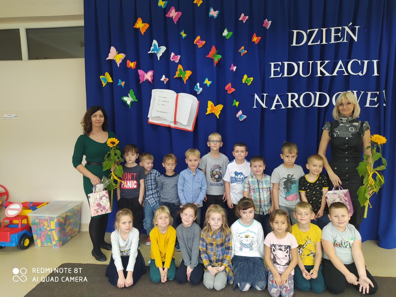 Grupa Reniferki wraz z paniami na tle dekoracji z napisem Dzień Edukacji Narodowej