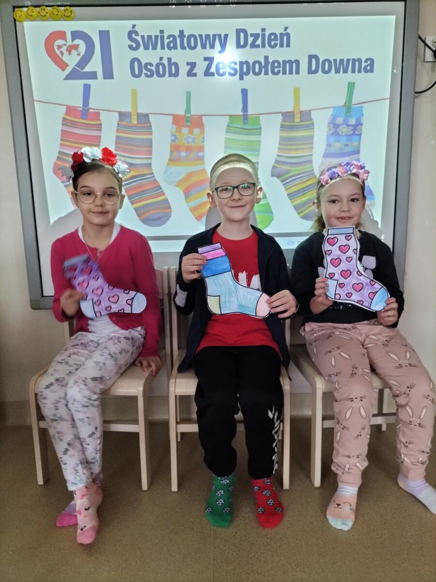 Zdjęcie przedstawia dzieci w wiosennych opaskach, które prezentują zaprojektowane przez siebie "kolorowe skarpetki".