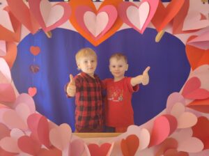 Zdjęcie ukazuje dwóch chłopców w fotobudce w kształcie serca.