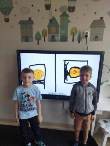 Chłopcy ze swoimi pracami na tablicy multimedialnej.