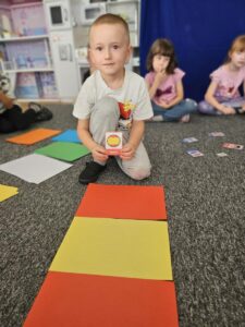 Chłopiec próbuje stworzyć flagę Hiszpanii z kolorowych kartek.