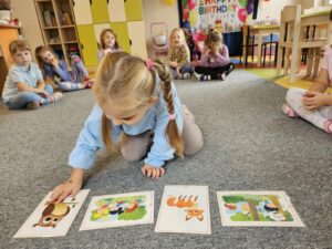 Dziewczynka rozkłada karty obrazkowe do piosenki.