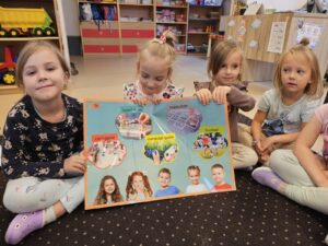 Dziewczynki prezentuja plakat ze słownictwem- zabawy i gry.