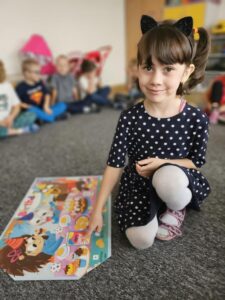 Dziewczynka wskazuje wybrane słówko przez nauczyciela na plakacie.