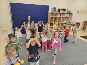 Dzieci pokazują żółtą piłeczkę.