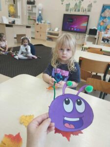 Dziewczynka nawleka listek na gąsieniczkę.