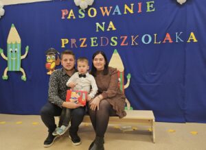 Rodzice z dzieckiem pozują do zdjęcia na ściance