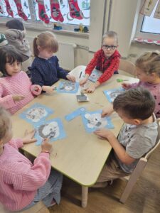 Zdjęcie ukazuje dzieci przy stoliku. Wykonują misia polarnego.