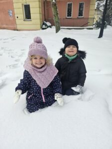 Dwójka dzieci w trakcie zabaw na śniegu.