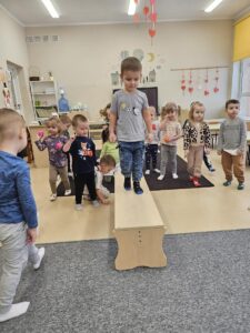 Chłopiec idzie po ławce , próbuje utrzymać równowagę.