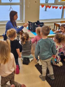 Nauczyciel ukazuje dzieciom legende o Smoku Wawelskim. Ba zdjeciu widać dzieci obserwujące nauczyciela.