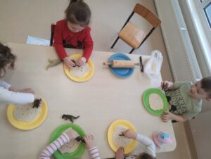 Dzieci przy stolikach robią odciski w masie solnej.