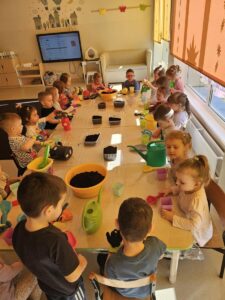 Dzieci wypełniają ziemią dobniczki.